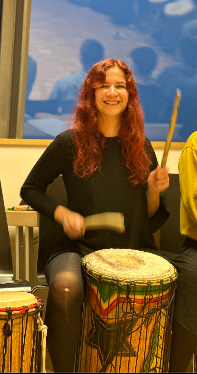 Participant playing a drum during a creative learning activity